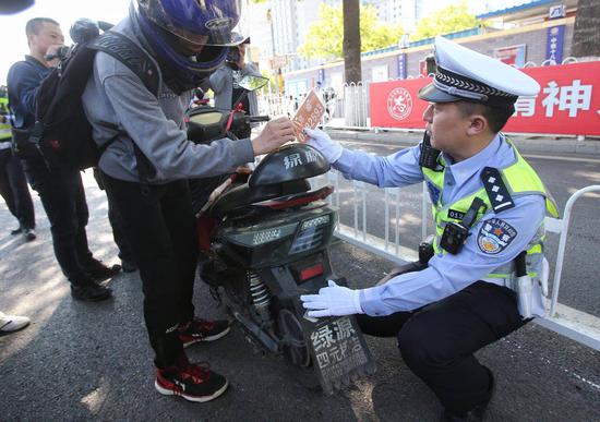 在宣武门路口，交警拦停下了一辆未按规定悬挂临时标识的电动车申领号牌，按规定对驾驶人处以20元罚款。新京报记者 王贵彬 摄